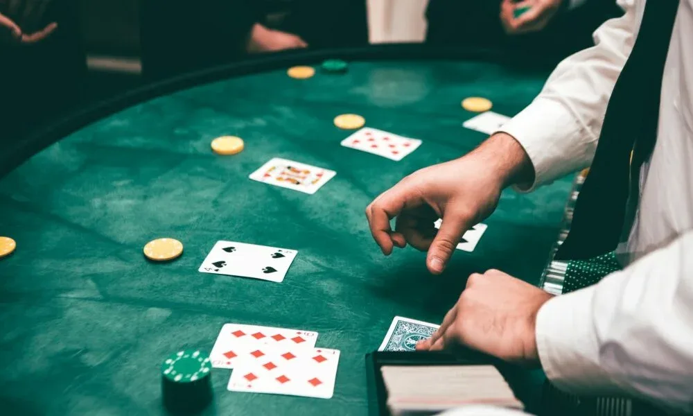 Un crupier reparte cartas sobre el paño de una mesa de blackjack, fotografía del blog de la marca.