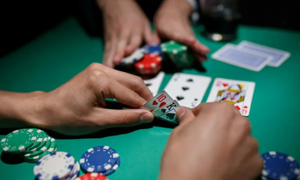 Manos de dos jugadores moviendo fichas y cartas sobre un paño verde, foto del blog de la marca.